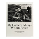 The cover of Andy Clark's book "My Camera Always Within Reach", with a photography of a man standing in front of a tiger's cage, while the tiger holds its paws over the man's face (hopefully in a playful way)
