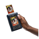 Hand holding a portable photo printer displaying a photo of two people with a white background