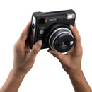 Hands holding a black instant camera against a white background