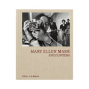 Mary Ellen Mark Encounters book cover with black and white photo of a woman holding a camera and title text on beige background