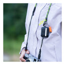 Camera with a camera strap, worn by a person wearing a light-colored jacket.