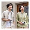 Two people standing outdoors, each holding a camera, with a neutral background.
