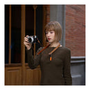 Woman holding a camera in front of a brick wall