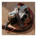 Camera with a black and red strap on a wooden surface