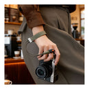 Person holding a camera with a strap in a cafe setting