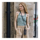A woman stands with her phone hanging on the PGYTECH LinkGo braided phone strap