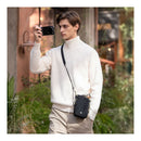 A man taking photos outdoors with a black crossbody bag.