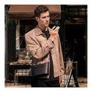 A person in a beige jacket takes a photo with a compact camera while wearing the OneGo Classic in black.