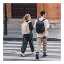 A man and a woman crossing the street wearing PGYTECH backpacks
