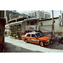Orange taxi parked in an urban alley captured on Reflx Lab 100 Daylight 35mm film