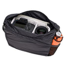 Tenba Tools Packlite compact camera bag with camera and lens inside, black lightweight carry bag with side mesh pocket