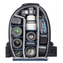 Open ThinkTank FirstLight camera backpack showing organized compartments with DSLR camera, multiple lenses, batteries, and accessories inside