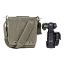 ThinkTank Retrospective 20 gray shoulder bag with adjustable strap next to DSLR camera and lenses on white background