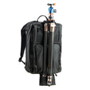 A black backpack with a tripod attached, on a white background