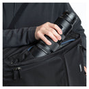 Person placing a camera lens into a black backpack