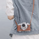 Nikon Z fc camera in SmallRig leather half case with shoulder strap hanging on person